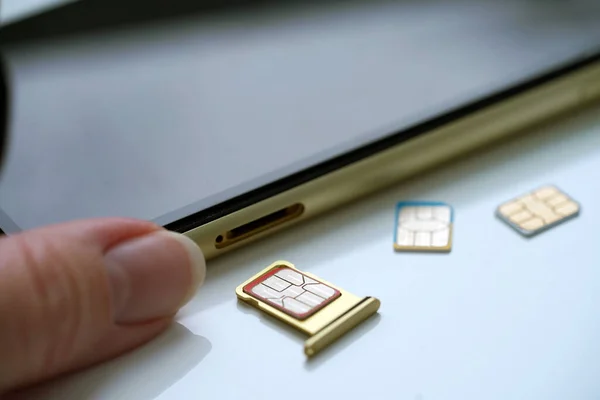 Person holding a sim card into back of mobile phone, Sim card in tray being inserted into phone, closeup
