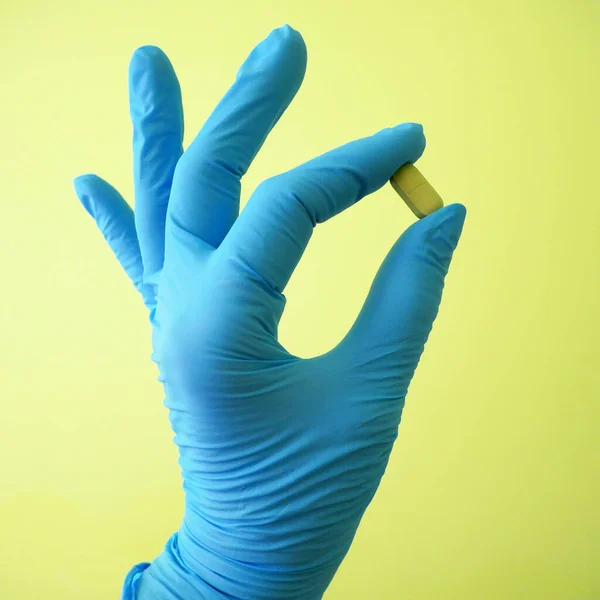 stock image Hand in blue medical gloves  holding pills  on green background, closeup