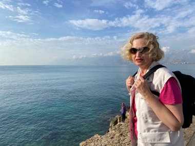 Sırt çantalı orta yaşlı kadın deniz sahilinde fotokopi odasıyla kalıyor. Yaz aktif turizmi, macera eskimez, açık hava