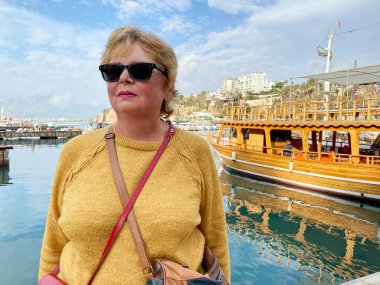 Antalya Türkiye 'nin eski kentinde marinada gemi, yat ve teknelerin yanında kalan sırt çantalı yaşlı kadın. Emekliler için yaz turizmi. Macera yaşsızdır, açık havada.
