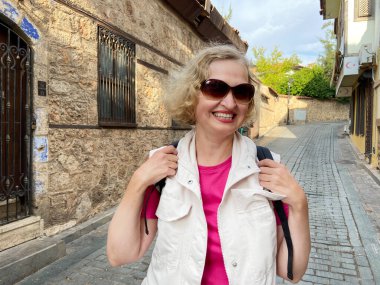 Sırt çantalı yaşlı kadın eski Antalya Hindi 'sinde yürüyor. Emekliler için yaz turizmi. Macera yaşsızdır, açık havada.