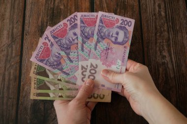 Ahşap arka planda Ukrayna Hryvnia parasından büyük bir deste tutuyor. Para nakit, yakın plan.