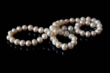 Beautiful white pearls necklace on black background, top view, closeup clipart