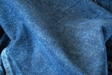 Mavi kot arka plan, doku. Mavi buruşuk, kot pantolon aşındırıcı kumaş. Kumaş kumaş. Arka plan olarak kullanılabilen mavi kot. Yakın çekim.