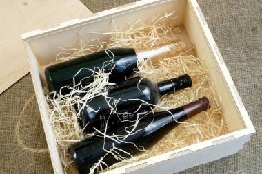 Tahta bir kutuda pahalı elit şarap şişeleri talaş, şarap tatma, internetten sipariş ve koronavirüs zamanında şarap teslimatı, İnternet şarap dükkanları konsepti. Yakın çekim.