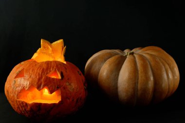 Siyah arka planda izole edilmiş şeytani bir yüzü ve gözleri olan Cadılar Bayramı Balkabağı 'nın parlayan Jack o feneri.