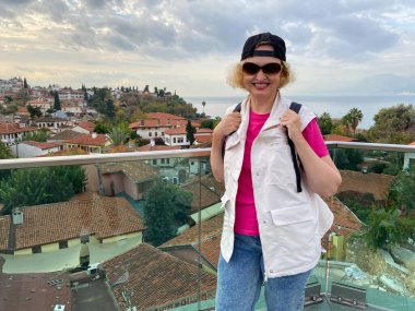 Sırt çantalı orta yaşlı kadın eski Antalya Türkiye şehrinde gemi, yat ve teknelerin yanında kalıyor. Emekliler için yaz turizmi. Macera ölümsüzdür.