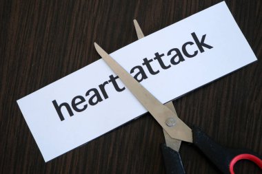 Kağıt kesme makası siyah ahşap zemin üzerinde HEART ATTACT metin kağıt, başarılı tedavi stratejisi, konsept
