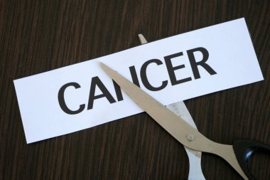 Makas kağıt parçalarını siyah ahşap zemin üzerinde CANCER ile kesiyor, başarılı tedavi stratejisi, konsept