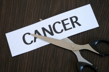 Makas kağıt parçalarını siyah ahşap zemin üzerinde CANCER ile kesiyor, başarılı tedavi stratejisi, konsept