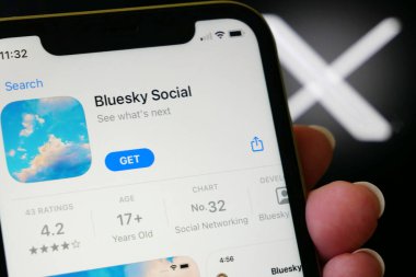 Lviv, Ukrayna - 09 25 2023: Twitter ve BlueSky. iPhone ekranında bir uygulama mağazasında Twitter 'a alternatif Bluesky Sosyal medya. X twitter sosyal medya logosu üzerinde Bluesky uygulaması olan el ele tutuşan iPhone, yakın plan