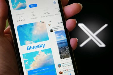 Lviv, Ukrayna - 09 25 2023: Twitter ve BlueSky. iPhone ekranında bir uygulama mağazasında Twitter 'a alternatif Bluesky Sosyal medya. X twitter sosyal medya logosu üzerinde Bluesky uygulaması olan el ele tutuşan iPhone, yakın plan