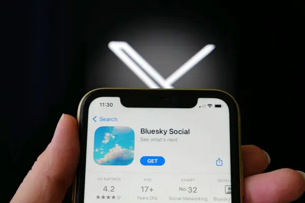 Lviv, Ukrayna - 09 25 2023: Twitter ve BlueSky. iPhone ekranında bir uygulama mağazasında Twitter 'a alternatif Bluesky Sosyal medya. X twitter sosyal medya logosu üzerinde Bluesky uygulaması olan el ele tutuşan iPhone, yakın plan