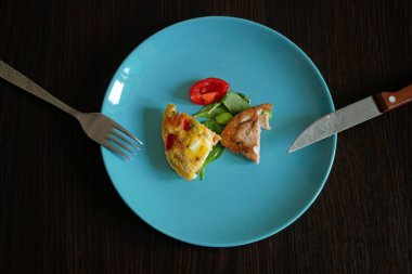 Yarısı yenmiş kahvaltı, kızarmış tavuk fileto ve taze sebze salatası, mangold ve roka yaprakları siyah ahşap arka planda. Tavuk etli salata. Sağlıklı yiyecekler. Düz yatıyordu. Üst görünüm.