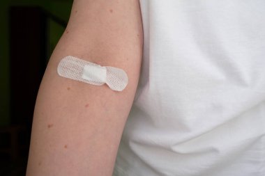 Kolunda yara bandı olan hasta bir kadının eli. Hastane, kan testi, yakın plan.