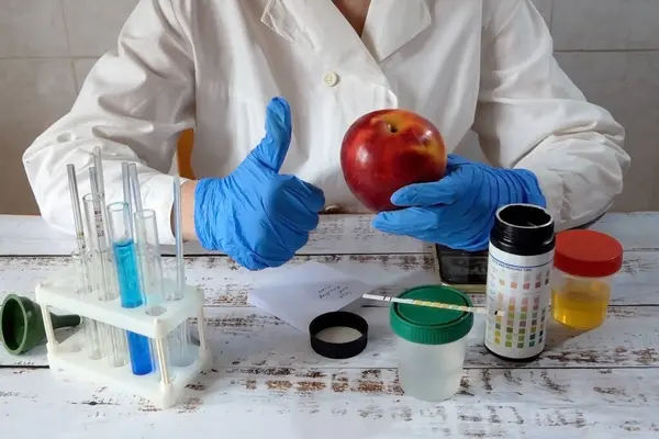 Medical laboratory assistant taking apple on  test tube with liquids background, test with urine, Scientist doctor looking at sample in test tube. Laboratory analysis. Closeup