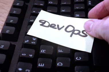 dizüstü bilgisayar klavyesi ve el, kağıt çıkartmasını devops başlığı, yazılım karmaşası kağıt görev ile çevik tahta, konsept koyar,