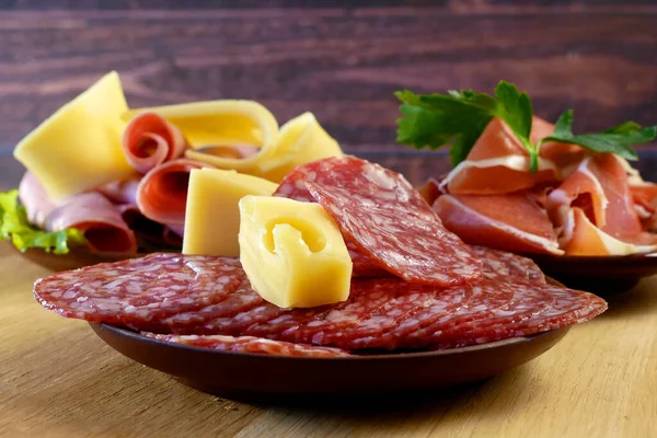 Cold Smoked Meat, jamon, sausage, cold meat, cheese. Plate, antipasto set platter wooden plate. Cold smoked meat plate with sliced ham, prosciutto, bacon. Closeup