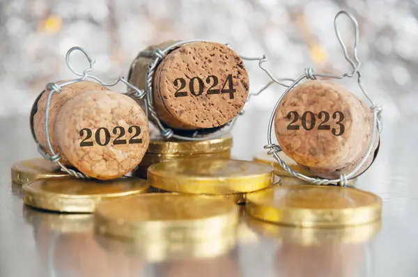 Neujahrsdekorationen Auf Leuchtendem Hintergrund Mit Kopierraum Schokoladenmünzen Und Champagnerkorken 2024 lizenzfreie Stockbilder