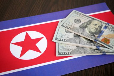 Kuzey Kore 'nin ulusal bayrağı ve Amerikan dolarlarının büyük bir yığını. ABD 'nin Kuzey Kore ülkesine destek ve yardım ve finans kavramı