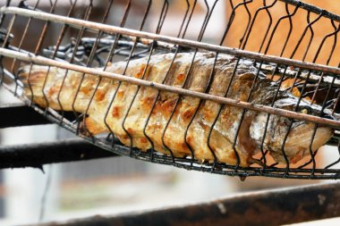 Kömürde kızartılmış balık. Izgara tabağında aromatik baharatlarla deniz ürünleri pişiren yakın çekim. Açık havada yaz bahçesinde barbekü.