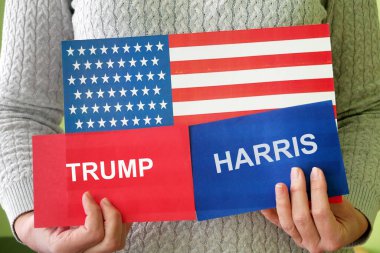 Washington, ABD - 2 Temmuz 2024: ABD bayrağı taşıyan kadın, Trump yazıtlı kırmızı kart ve HARRIS yazıtlı mavi kart. Başkan seçimleri konsepti. HARRIS Trump Konseptine Karşı.