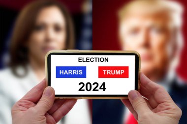 Washington, ABD - 16 Eylül 2024: seçim bölgesi ile el ele tutuşan moline telefon ve TV haber arka planında Kamala Harris ve Donal Trump. - Evet. Donald Trump, Kamala Harris 'e karşı ABD Başkanı. ABD seçimleri 2024