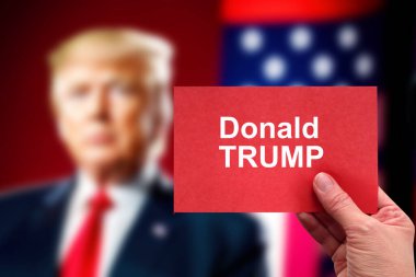 Washington, ABD - 16 Eylül 2024: TV arka planında Trump portresi üzerinde Donald Trump başlıklı kırmızı kart. ABD seçimleri 2024