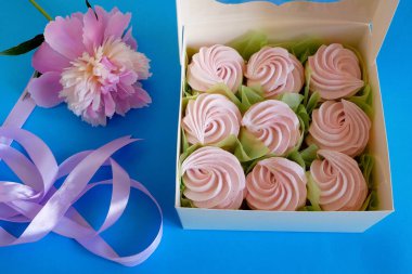 İçinde renkli kurabiyeler, bir kutu Zefir, Zephyr ve çiçeklerle dolu beyaz bir kutu. Bir kutu zephyr. Şekerleme ve şakayık çiçeği. Üst görünüm