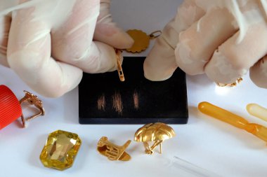 Rehinci dükkanı çalışanı, eski altın mücevherlerini bir mihenk taşı kullanarak test ediyor ve eski altınları alıyor.