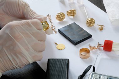 Rehinci dükkanı çalışanı, eski altın mücevherlerini bir mihenk taşı kullanarak test ediyor ve eski altınları alıyor.