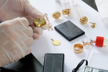 Rehinci dükkanı çalışanı, eski altın mücevherlerini bir mihenk taşı kullanarak test ediyor ve eski altınları alıyor.