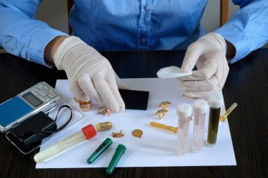 A pawn shop employee tests old gold jewelry using reagents and a touchstone, Buying old gold clipart