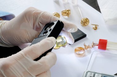 Rehinci dükkanı çalışanı, eski altın mücevherlerini bir mihenk taşı kullanarak test ediyor ve eski altınları alıyor.