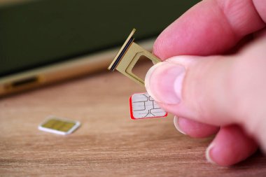 Person inserting a sim card into back of mobile phone, Sim card in tray being inserted into phone, closeup