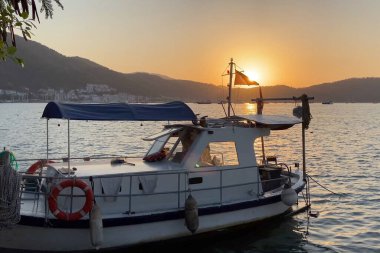 Dağın arka planında, açık havada teknelerle denizde gün batımı