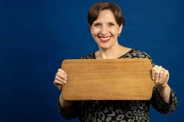 看板としてまな板を持っている幸せな年上の女性 木製ボード上のコピーのための部屋と高品質の写真 — ストック写真