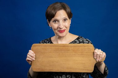 Mutlu yaşlı kadın işaret olarak kesme tahtası tutuyor. Tahtada kopyası olan yüksek kaliteli bir fotoğraf.