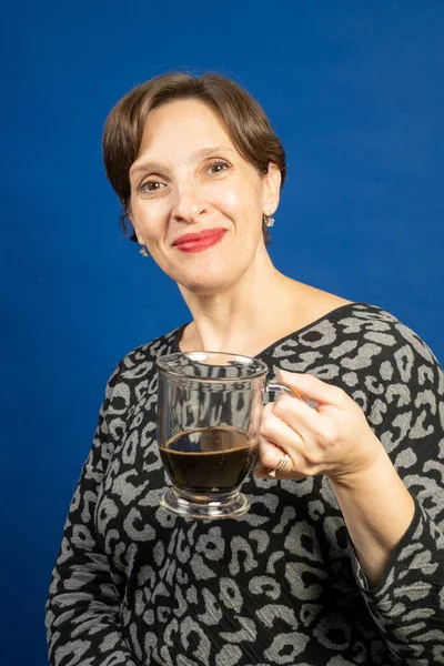 黒コーヒーを楽しんでいる女性 青い背景に高品質のスタジオ写真が撮られました — ストック写真