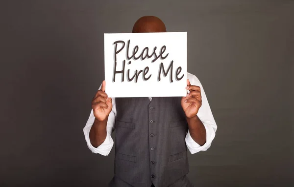 Please Hire Me - Young black businessman holding a white card indicating desire to work