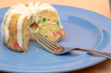 Confetti Bunt Cake on blue plate with cream cheese frosting