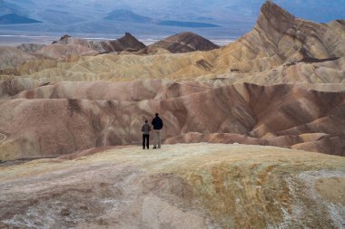A couple enjoys the view of the sunset from Death Valley. High quality photo taken at Zabriskie Point 