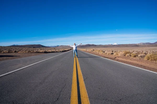 腕を伸ばして砂漠の道の真ん中に立っている老人 高品質の写真 — ストック写真