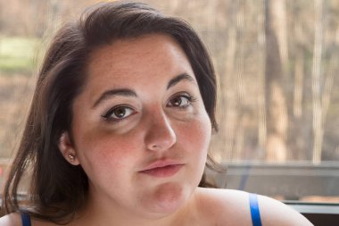 Artı boyut esmer kadın, doğal ışıkta saten gecelikle poz veriyor.