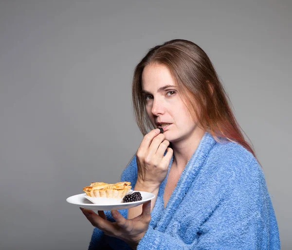 Sallow Niezdrowo Wyglądająca Kobieta Jedząca Owoce Ciastka Niebieskim Szlafroku Patrząca — Zdjęcie stockowe