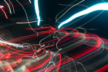 Görüntü bulanık, renkli ve bir arabanın farlarının dinamik bir temsilidir. Işık çizgileri bir hareket ve enerji hissi yaratıyor, heyecan ve hız hissi uyandırıyor.