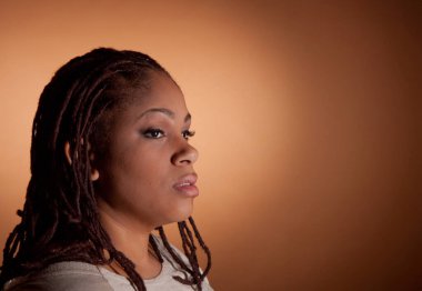 Rastalı bir kadın kameraya bakıyor. Yüzünde ciddi bir ifade var.