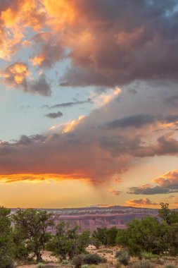 Gökyüzünde birkaç bulut olan bir sıradağda güzel bir günbatımı. Gökyüzü turuncu ve pembe renklerin karışımıdır. Sıcak ve huzurlu bir atmosfer yaratır.