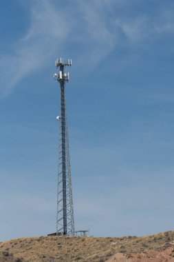 Modern cep telefonu kulesi ince bulutlu parlak mavi gökyüzüne karşı. İletişim konsepti.