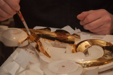 Sanatçı süsü gerçek altınla süslemiş. Kuyumcu. Eller ve fırça